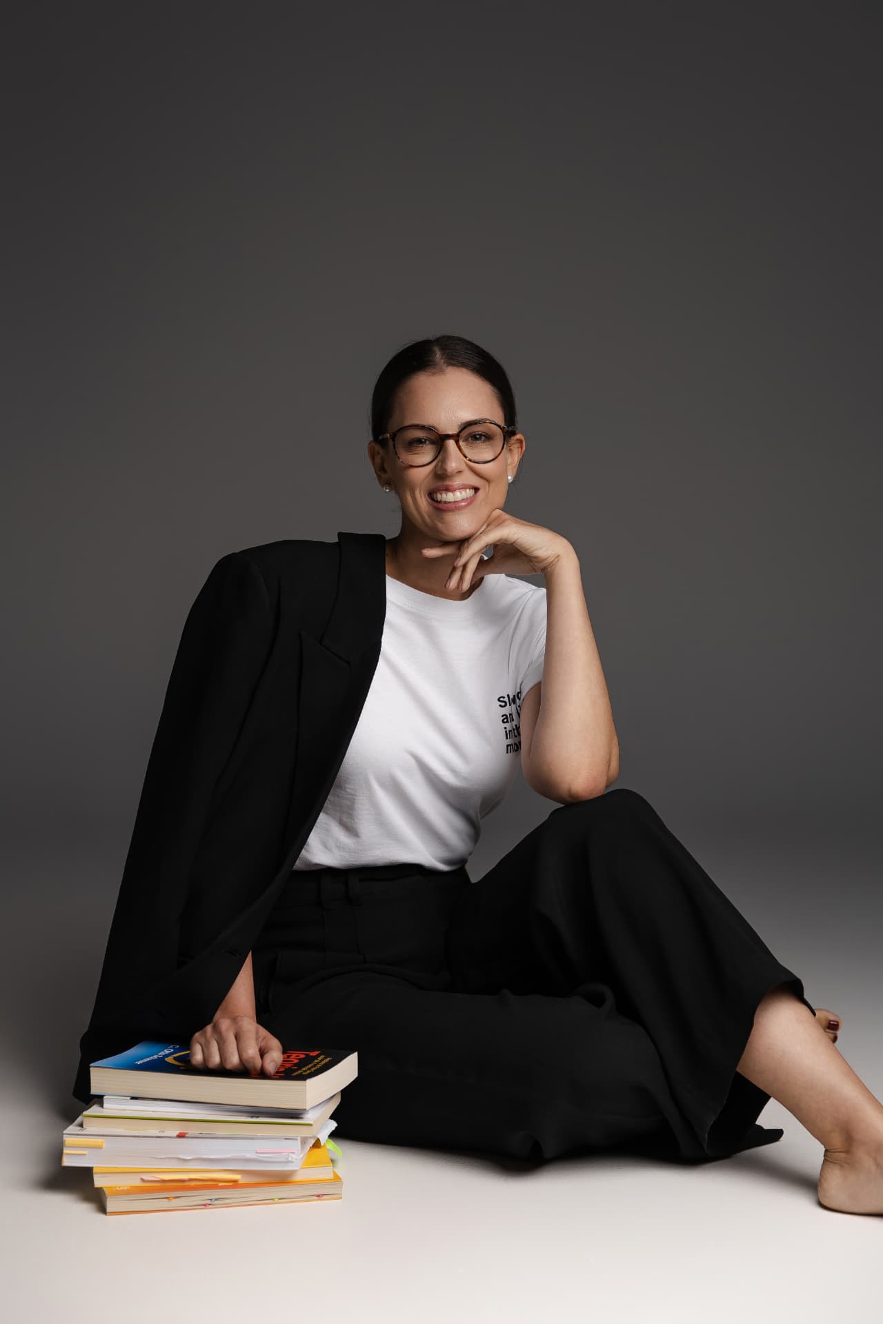 Carol Bellini sentada ao lado de livros