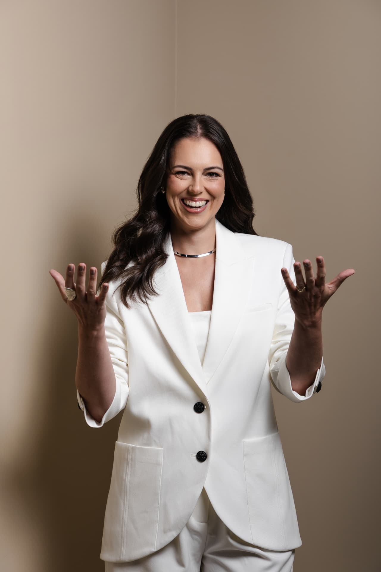 Carol Bellini em pé, vestindo terno branco